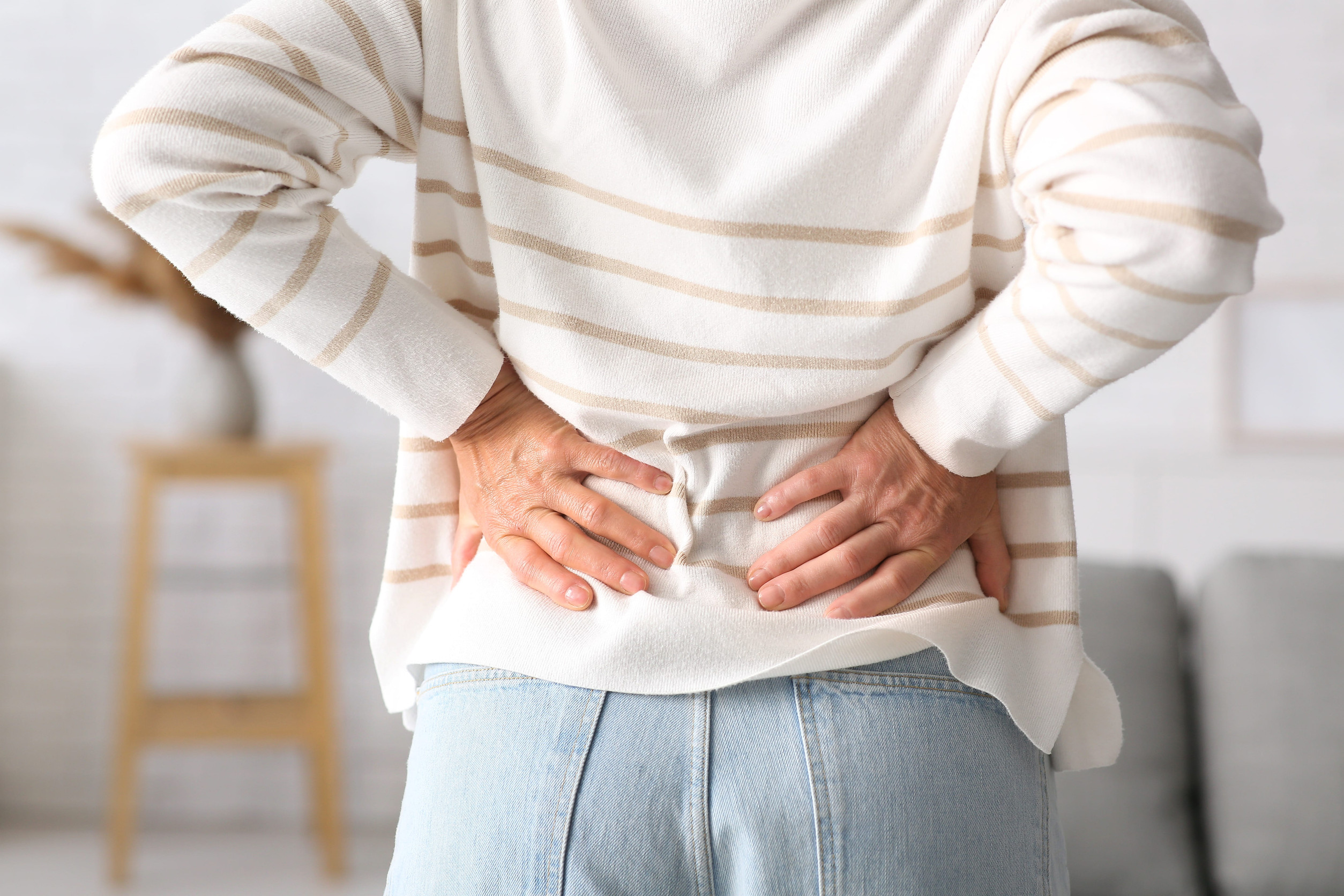Mature woman suffering from back pain at home,